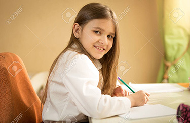 Portrait of smiling girl in white shirt sitting behind desk and